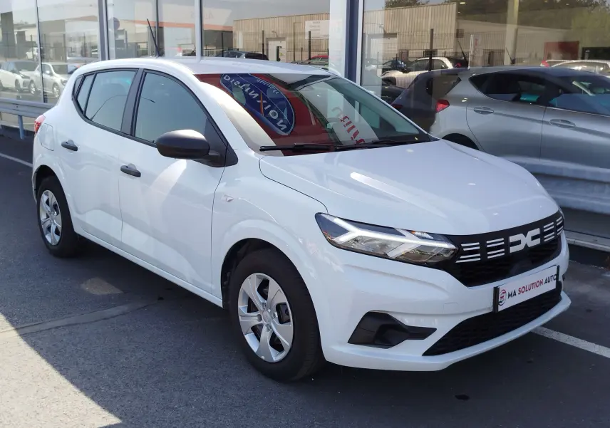 Vue 3/4 avant droite d'une Dacia Sandero blanche Glacier 2025 avec calandre noire et feux LED distinctifs.