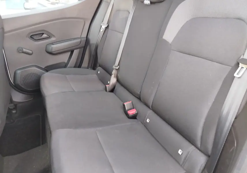 Vue intérieure côté droit des sièges arrière noirs de la Dacia Sandero 2025, avec ceinture de sécurité et accoudoir de porte.