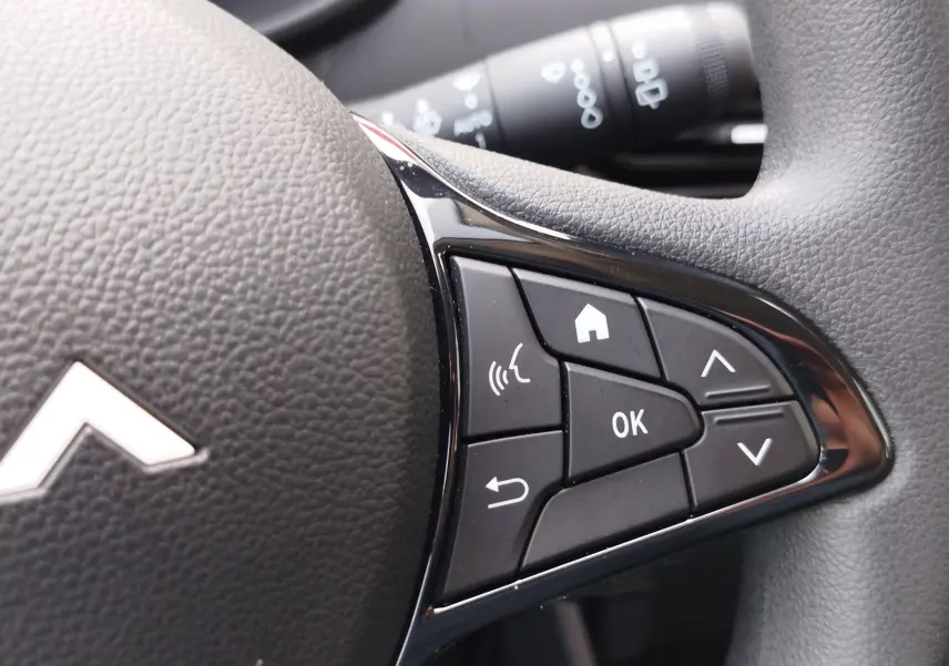 Gros plan sur les commandes multifonctions à droite du volant noir de la Dacia Sandero 2025, finition Essentiel.