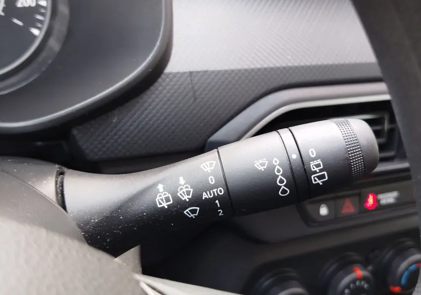 Gros plan sur la commande des essuie-glaces dans l’habitacle gris d’une Dacia Sandero Blanc Glacier 2025.