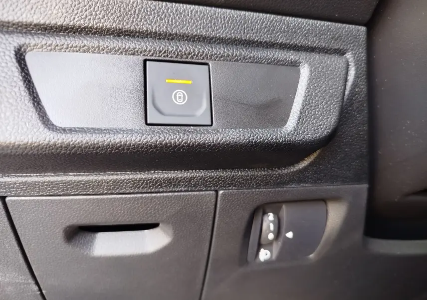 Gros plan sur le bouton de verrouillage centralisé avec témoin orange dans l'habitacle noir du Dacia Sandero 2025.