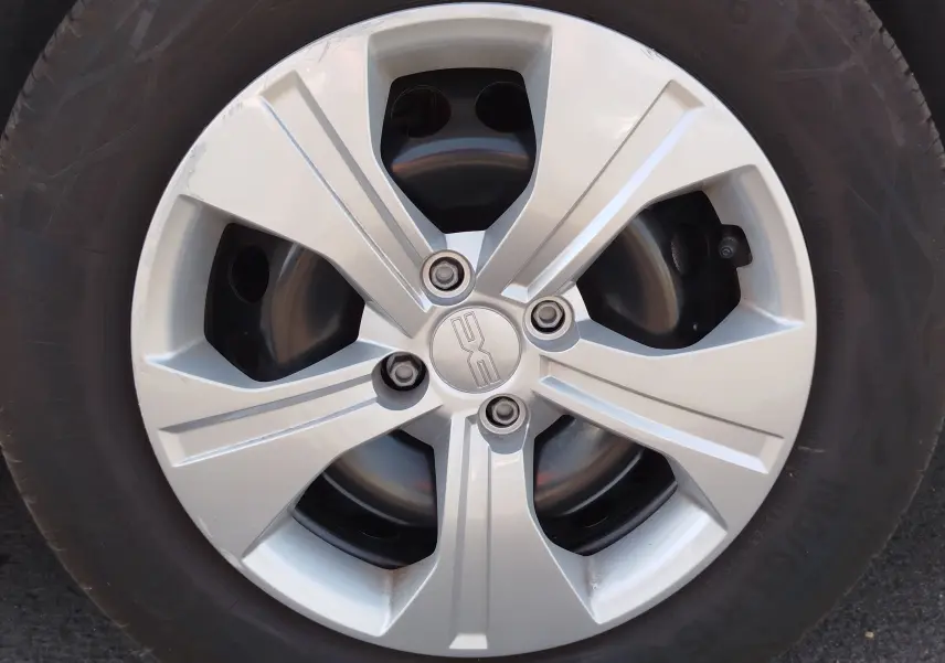 Gros plan sur la jante argentée de la roue d’une Dacia Sandero Blanc Glacier, avec logo central DACIA visible.