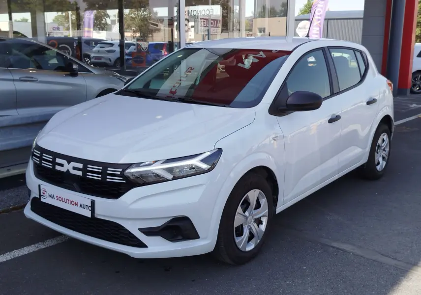 Dacia Sandero blanc Glacier vue 3/4 avant droit, avec calandre noire distinctive et jantes acier.
