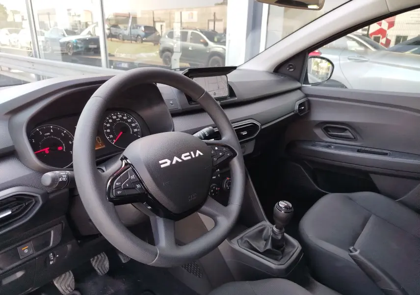 Vue intérieure côté conducteur de la Dacia Sandero 2025, volant multifonction et levier de vitesse manuel visibles.