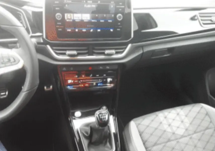 Vue intérieure centrée sur la console centrale et levier de vitesse manuel du Volkswagen T-Roc gris platinium 2025.