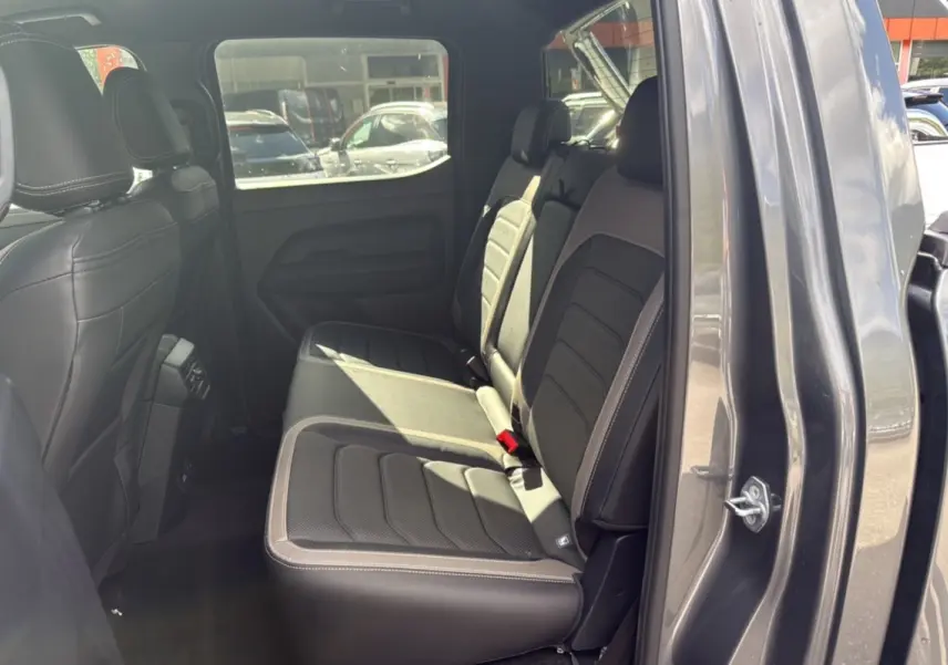 Vue latérale droite de l'intérieur arrière du Volkswagen Amarok Simple Cabine 2025 gris foncé avec sièges en cuir noir.