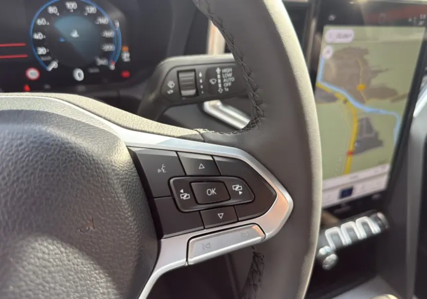 Gros plan sur le volant et les commandes du Volkswagen Amarok Simple Cabine 2025, avec écran tactile et navigation visible.