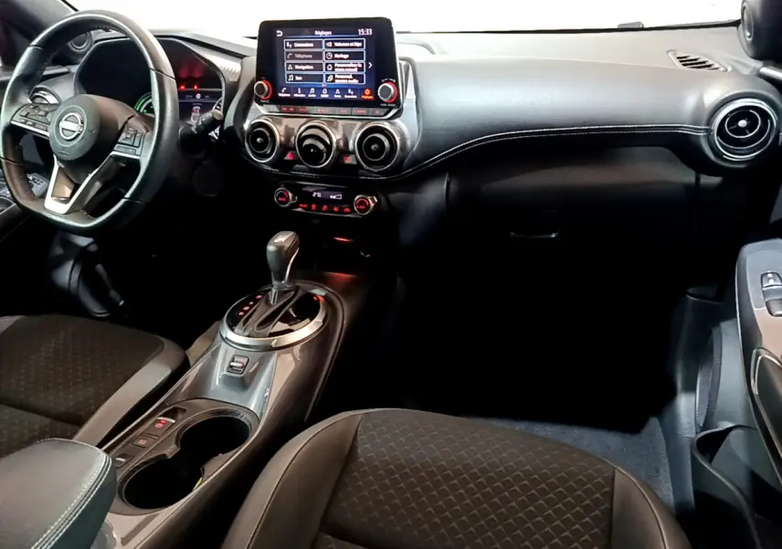 Intérieur du Nissan Juke Hybrid 143 Business+ 2023, vue avant centrée sur tableau de bord et console gris foncé.