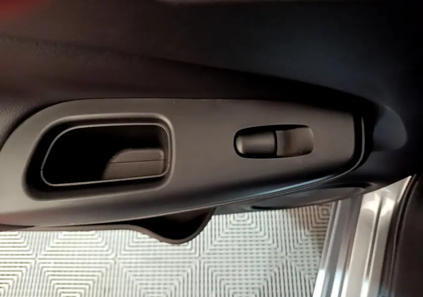 Poignée intérieure et commande de verrouillage côté gauche de la porte d'une Nissan Juke Hybrid gris foncé 2023.