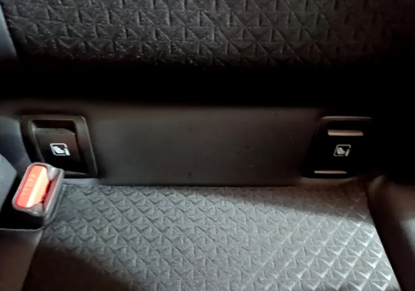 Détail de la banquette arrière grise avec boutons de rabattement des sièges et ceinture de sécurité du Nissan Juke Hybrid 2023.