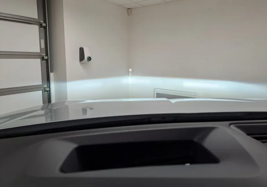 Vue depuis l’intérieur du Skoda Kodiaq gris argent, affichage tête haute projeté sur un mur blanc en garage.