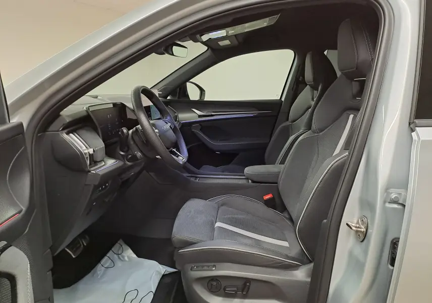Vue intérieure côté conducteur du Skoda Kodiaq gris argent 2025, sièges sport noirs avec surpiqûres grises et tableau de bord moderne.
