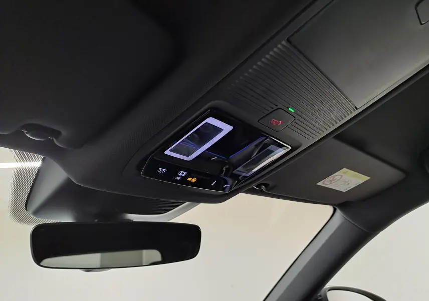 Vue intérieure du plafond avant du Skoda Kodiaq gris argent 2025, avec commandes d’éclairage et bouton SOS éclairé.