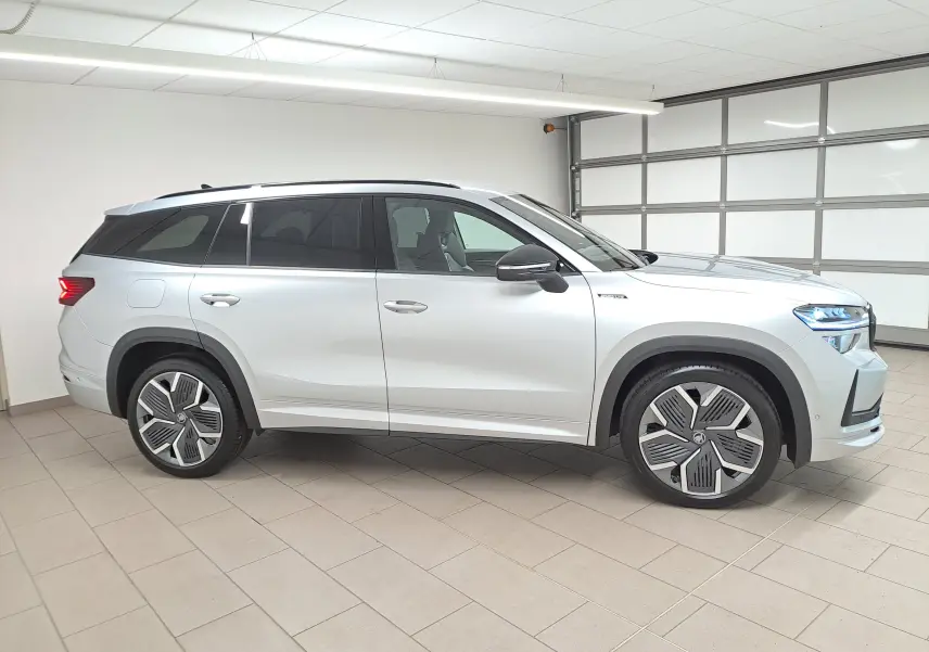 Vue de profil côté gauche d'un Skoda Kodiaq gris argent 2025 hybride rechargeable avec jantes 20 pouces et vitres teintées.