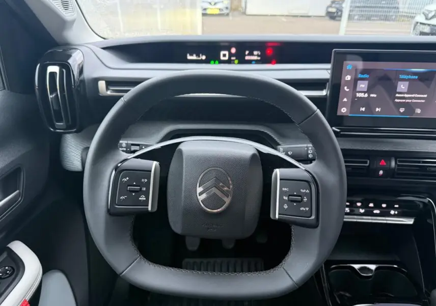 Vue intérieure centrée sur le volant de la Citroën C3 gris 2025, avec tableau de bord numérique et écran tactile.