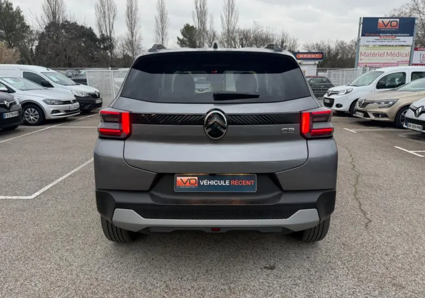 Vue arrière d'une Citroën C3 gris 2025 avec feux LED allumés et barres de toit visibles sur un parking.