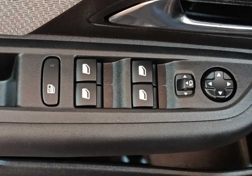 Gros plan sur les commandes de lève-vitres et réglages des rétroviseurs côté conducteur d'une Citroën C4 gris foncé.