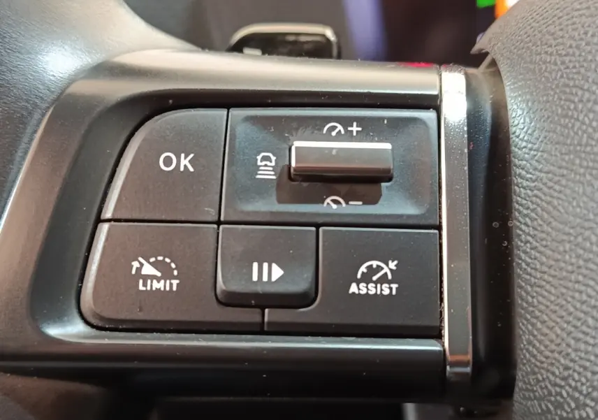 Gros plan sur les commandes noires du volant côté gauche de la Citroën C4 2022, avec boutons de régulateur et limiteur de vitesse.