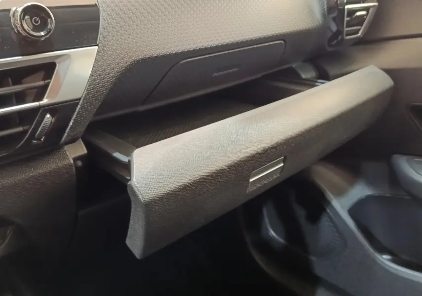 Gros plan sur la boîte à gants ouverte de l’habitacle noir d’une Citroën C4 2022, finition Shine.