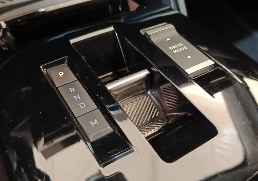 Gros plan sur la console centrale noire brillante de la Citroën C4 2022 avec sélecteur de boîte auto et bouton Drive Mode.