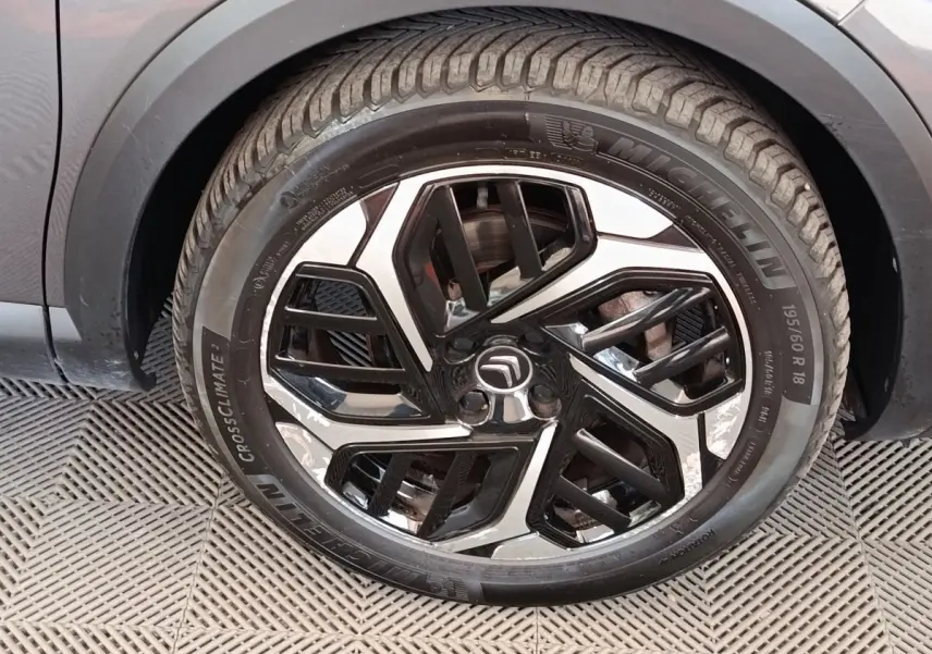 Gros plan sur la roue avant droite d'une Citroën C4 gris foncé, jante alliage bicolore au design moderne.