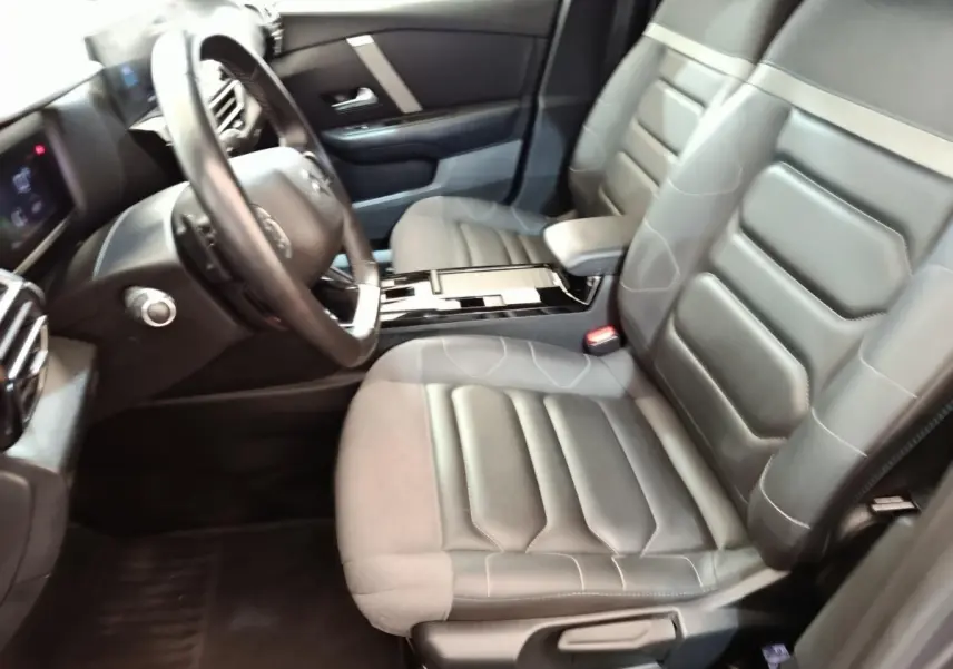 Vue intérieure côté conducteur de la Citroën C4 2022, sièges gris cuir et tableau de bord avec volant multifonctions.