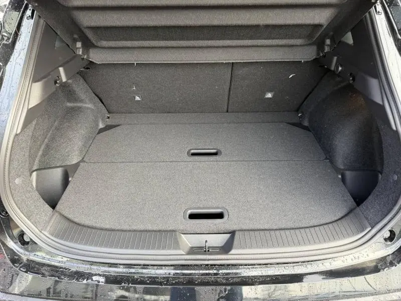 Coffre ouvert vu de l'arrière d'un Nissan Qashqai Hybrid e-POWER noir 2025, avec plancher de coffre plat et compartiments intégrés.