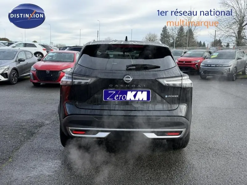Vue arrière d'un Nissan Qashqai Hybrid e-POWER noir 2025 avec logo et plaque Zero KM visible sur un parking.