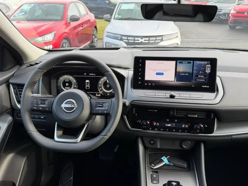 Vue intérieure du tableau de bord et volant du Nissan Qashqai Hybrid e-POWER 2025, avec écran tactile et commandes au volant.