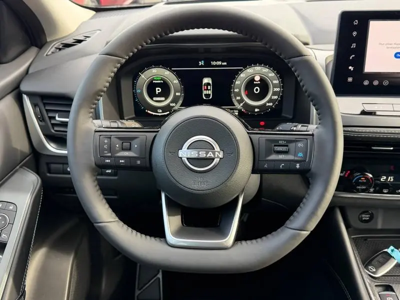 Vue frontale du volant cuir noir du Nissan Qashqai Hybrid e-POWER 2025 avec tableau de bord numérique et commandes intégrées.