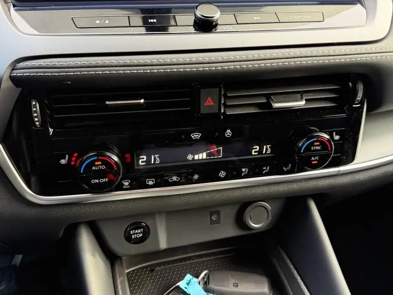Tableau de bord du Nissan Qashqai Hybrid e-POWER 2025 montrant la console centrale avec climatisation digitale et commandes tactiles.
