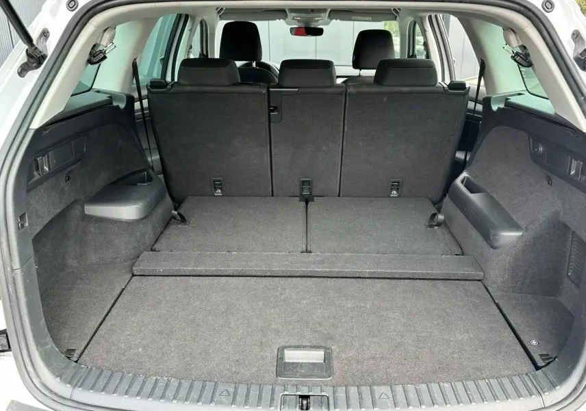 Coffre ouvert du Skoda Kodiaq blanc glacier 2024, montrant la banquette arrière rabattue et l'espace de chargement spacieux.