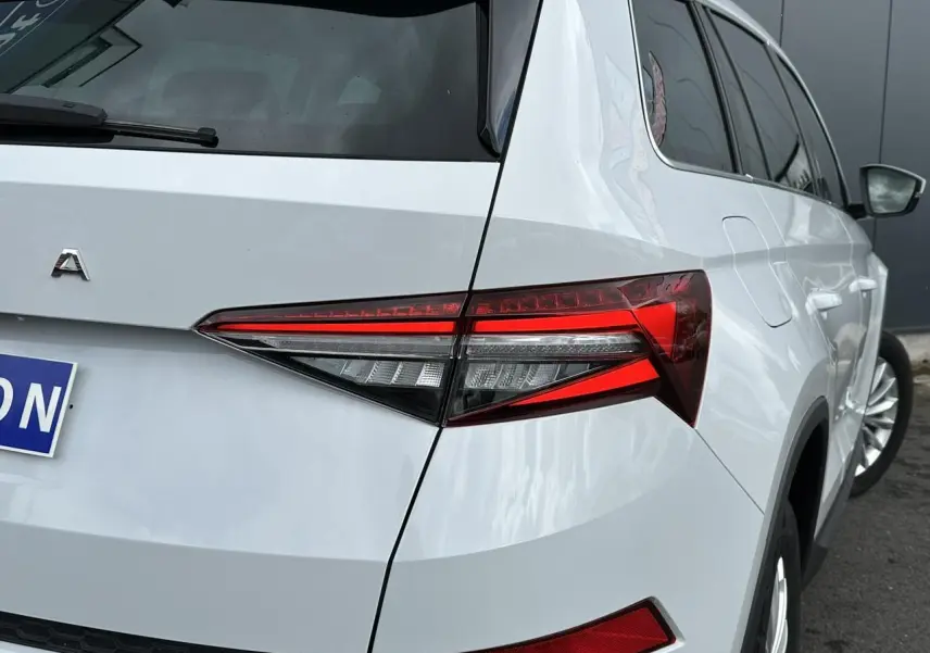 Vue 3/4 arrière droite d'un Skoda Kodiaq blanc glacier avec feux arrière LED et jantes alliage 18 pouces.
