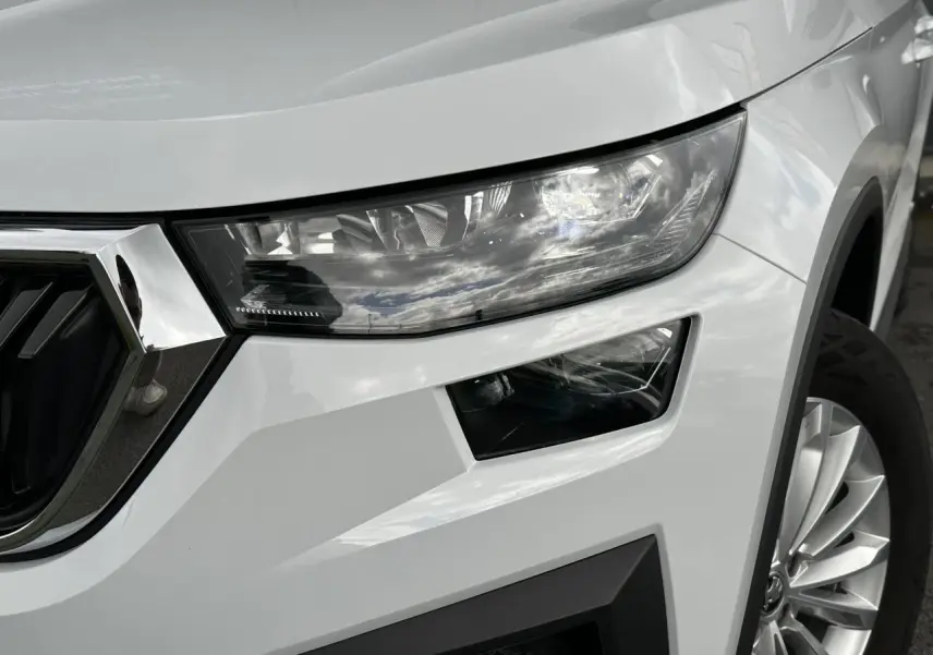 Gros plan sur l'avant droit du Skoda Kodiaq blanc Glacier, mettant en valeur le phare LED et la jante alliage 18 pouces.