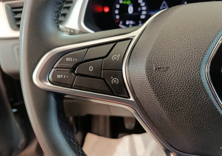 Gros plan sur les commandes du volant noir du Renault Captur Techno TCe 90 2024, affichage numérique en arrière-plan.