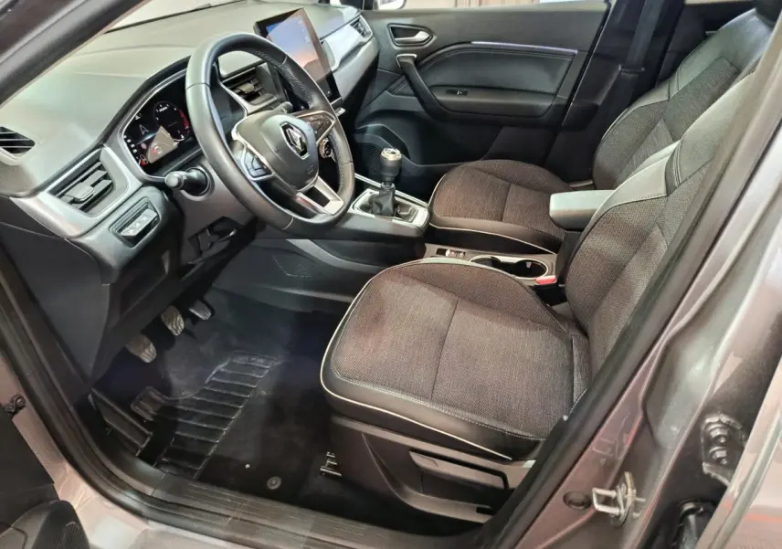 Intérieur avant droit du Renault Captur gris foncé 2024 avec tableau de bord numérique et boîte manuelle.