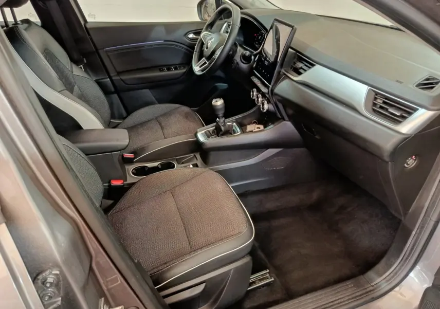 Intérieur côté conducteur du Renault Captur gris foncé 2024, avec tableau de bord moderne et boîte manuelle.