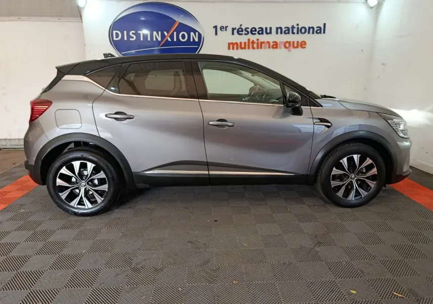 Profil côté gauche d'un Renault Captur techno TCe 90 gris foncé, avec jantes alliage et toit noir contrasté.