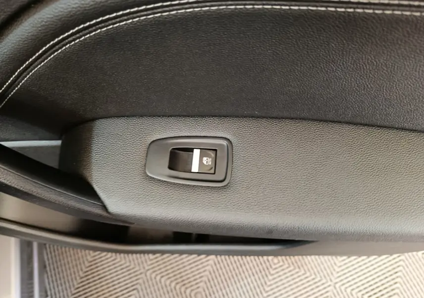 Gros plan sur le bouton de verrouillage des vitres sur la porte intérieure en cuir noir du Renault Captur gris foncé 2024.