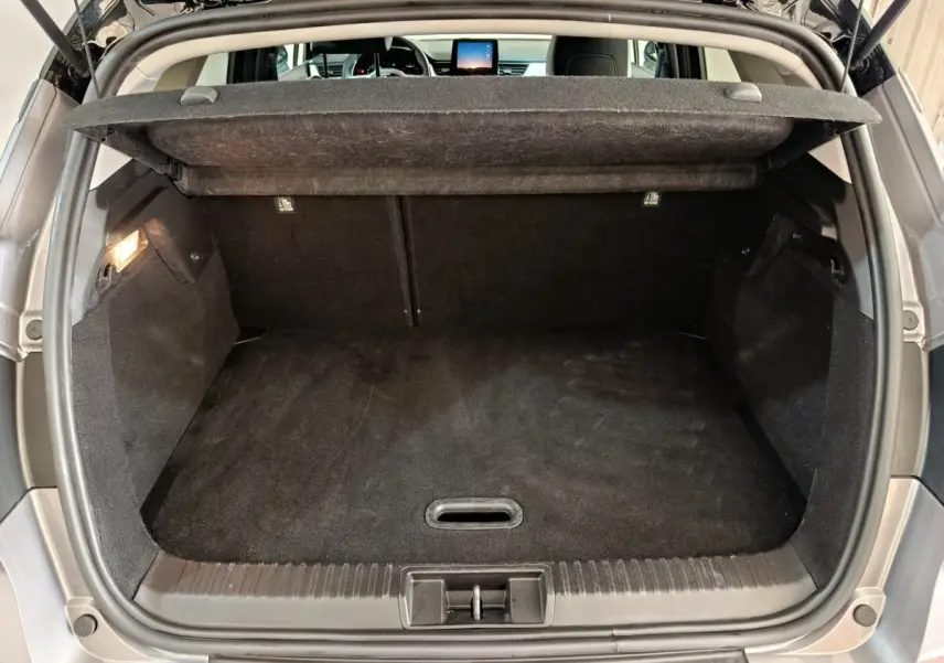 Coffre ouvert vu de l'arrière d'un Renault Captur gris foncé, montrant un espace de chargement propre et spacieux.