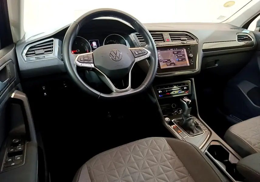 Intérieur du Volkswagen Tiguan 2021, vue du poste de conduite avec volant cuir multifonctions et écran tactile central.