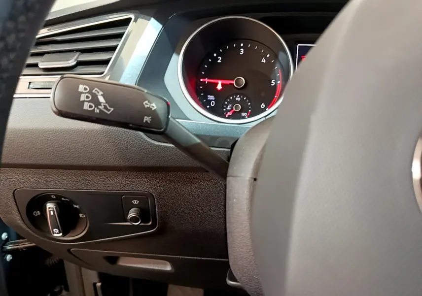Vue rapprochée du tableau de bord gris clair du Volkswagen Tiguan 2021, avec manette de clignotants et compte-tours visible.