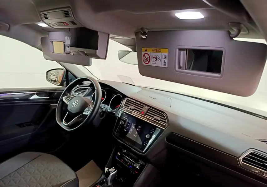 Intérieur du Volkswagen Tiguan gris clair vu côté conducteur, tableau de bord moderne avec écran tactile et volant cuir.