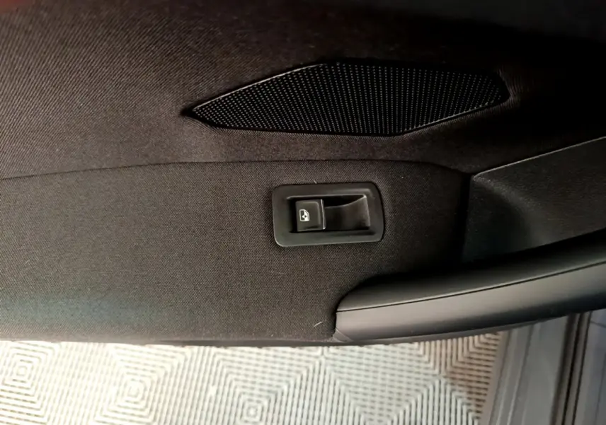 Détail de la commande de lève-vitre sur la porte intérieure noire du Volkswagen Tiguan gris clair 2021.