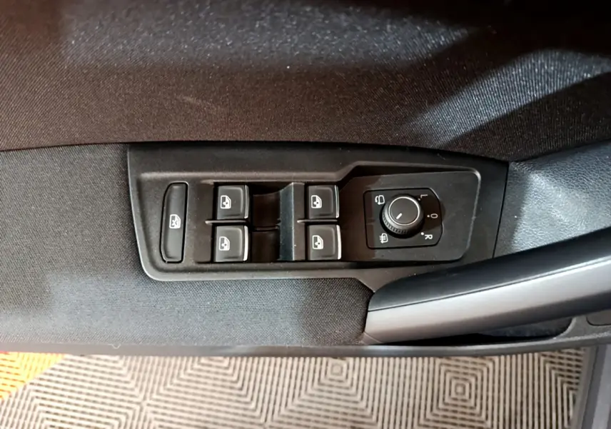 Gros plan sur les commandes de lève-vitres et réglage des rétroviseurs côté conducteur du Volkswagen Tiguan gris clair 2021.