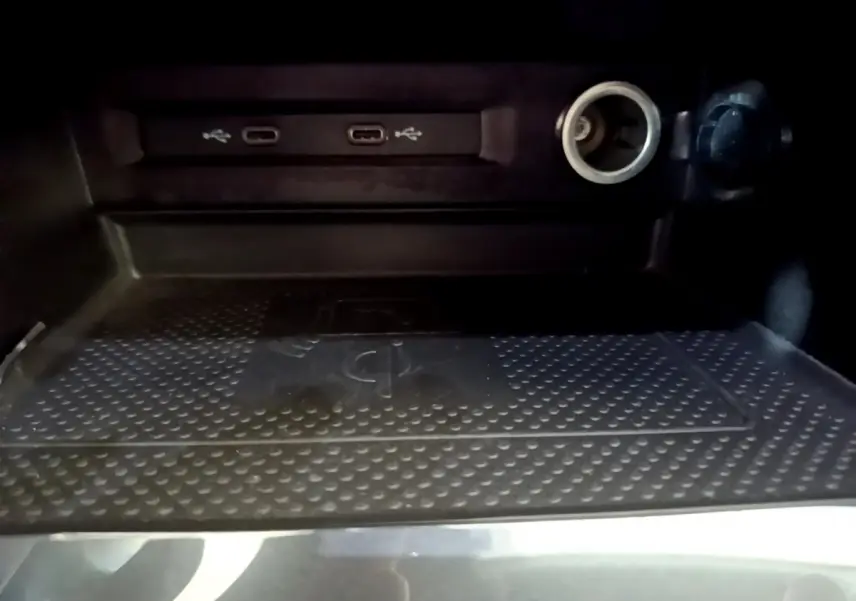 Gros plan sur la zone de recharge sans fil et ports USB-C dans le coffre du Volkswagen Tiguan gris clair 2021.