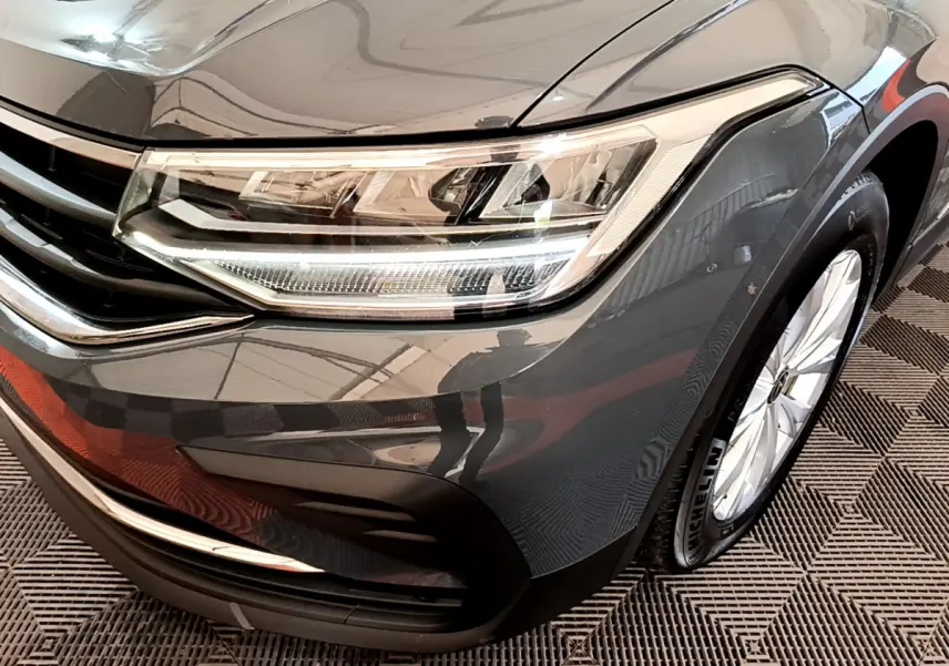Gros plan sur l'avant droit gris clair du Volkswagen Tiguan 2.0 TDI 150 DSG7 avec phare LED et jante alliage.