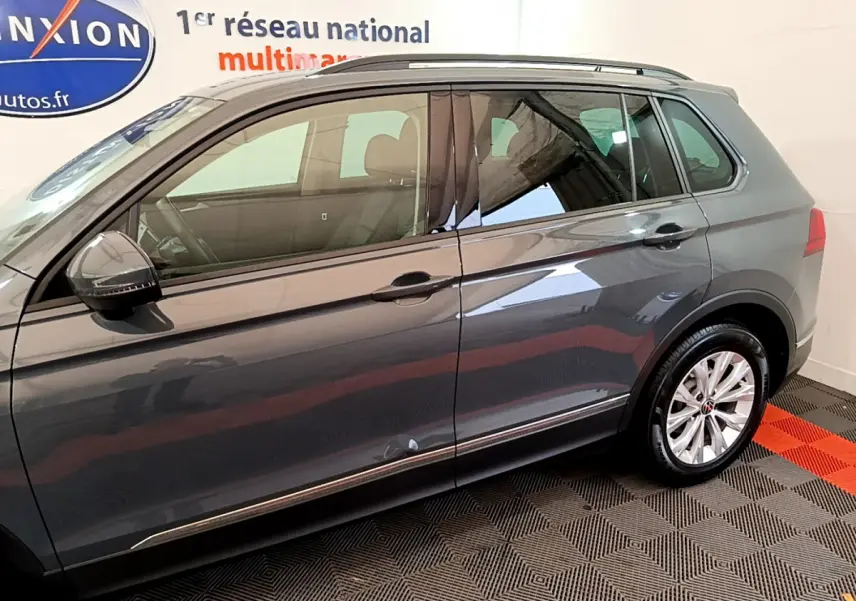 Profil côté gauche d'un Volkswagen Tiguan gris clair 2021 avec jantes alliage et rétroviseurs noirs brillants.
