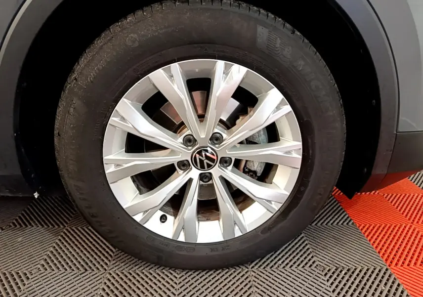 Gros plan sur la roue avant droite du Volkswagen Tiguan gris clair, jante alliage à multiples branches fines.