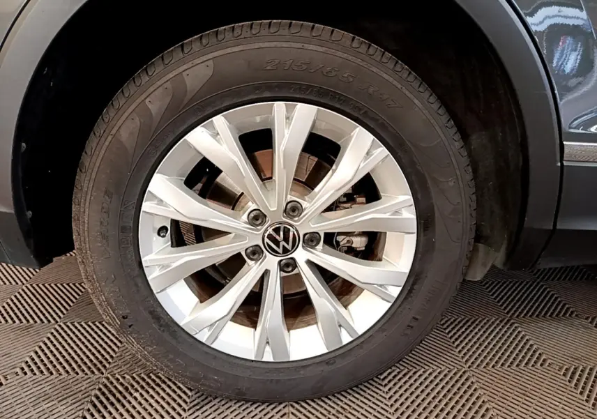 Gros plan sur la roue avant droite du Volkswagen Tiguan gris clair, mettant en valeur la jante en alliage moderne.